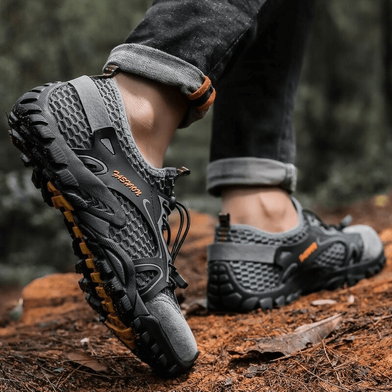 Men's waterproof non-slip climbing sneakers with patchwork design on woodland trail.